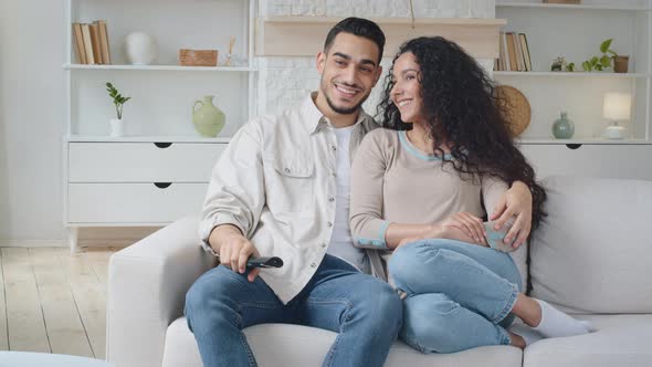 Spanish Couple Sitting on Couch at Home Enjoying Movie
