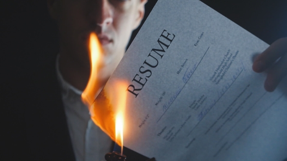 of Businessman Burns Resume Document in a Dark Background.