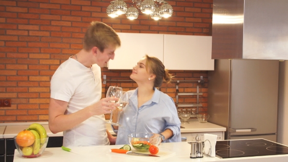 Happy Couple Drinking Wine and Eating Salad in the Kitchen at Home