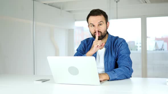Gesturing of Silence By Man Sitting in Office