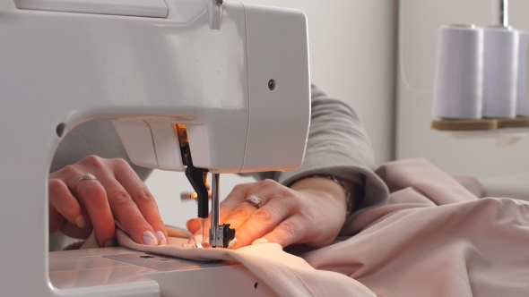 Footage of a Woman Sewing a Pink Cotton with a Sewing Machine.