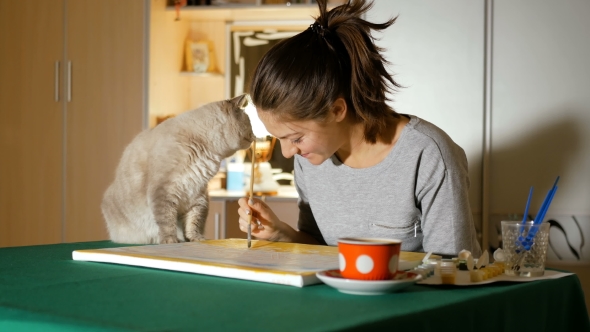 The Artist Tries To Paint a Picture at Home, but Her Gray Cat Prevents Her From Doing This