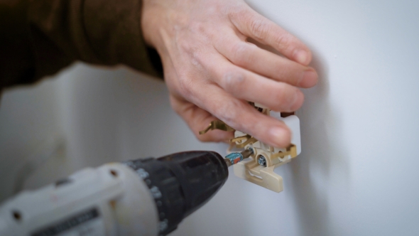 Electrical Fitter Is Spinning a Tiny Mounting Screw Inside a Socket for Fixing Wires Using alt