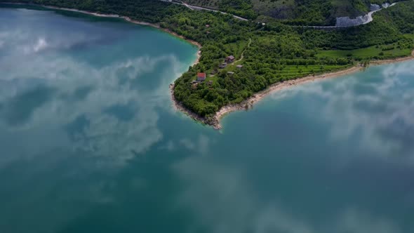 A lake in northern Croatia surrounded by greenery and mountains. The reflection of the sky and cloud