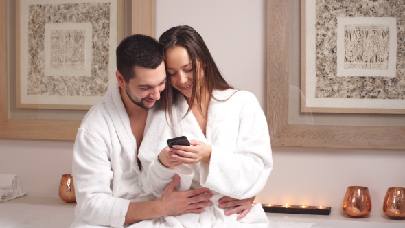 Happy Young Couple Uses Smartphone in Spa Center.