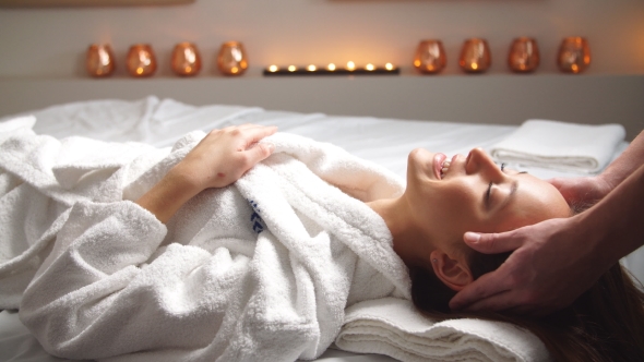 Attractive Young Woman Receiving Head Massage at Spa Center.