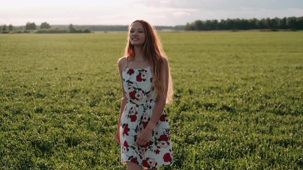 Happy Red-haired Woman Whirls in a Flowering Field at Sunset. Happy Red-hair Girl Whirls Around. Joy