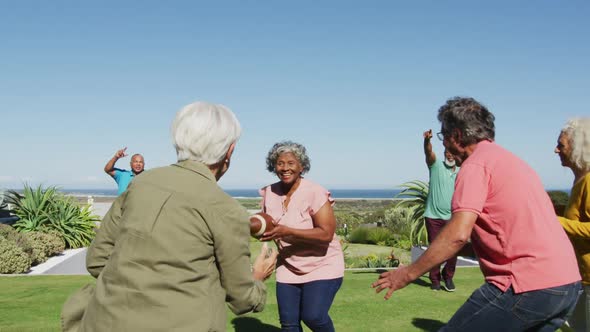 Happy senior diverse people playing rugby in garden at retirement home