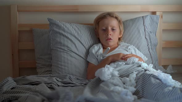 A Sick Little Boy in a Bed Mother Measures His Temperature Baby Flu Concept