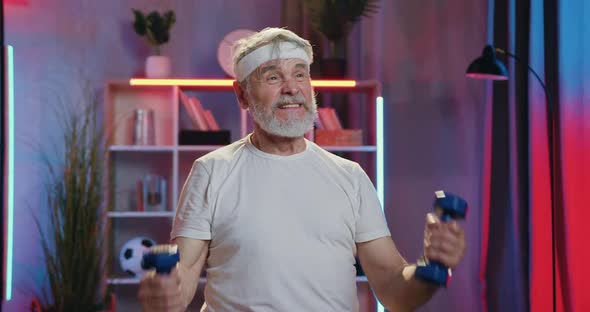 Old Man in Sportswear Intensive Doing Sports Exercises with Dumbbells During Home Evening Workout