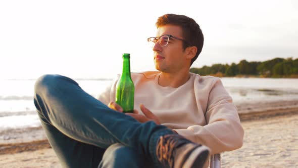 Man Drinking Beer Sitting on Chair on Beach