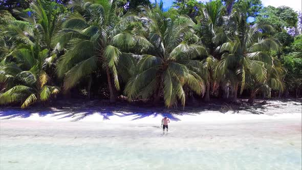 Young Man Diving into Crystal Clear Waters from the White Sand of the Beach