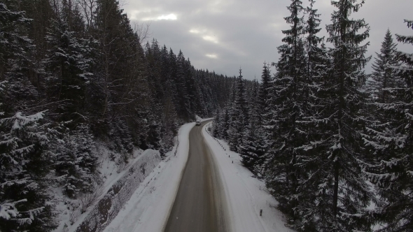 Car Driving on Winter Country Road in Snowy Forest, Aerial View From Drone