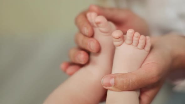 Mother's Hands Gently Touch the Little Feet of Her Baby