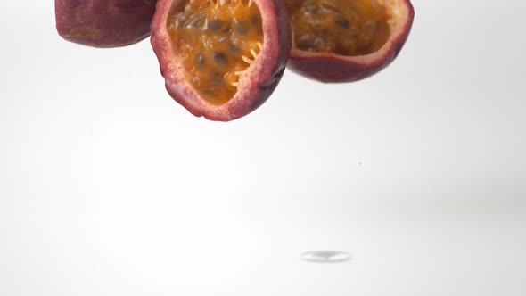 Passion fruit falling and bouncing on water surface. Slow Motion.