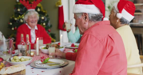 Happy caucasian senior man looking at camera, celebrating meal with friends at christmas time