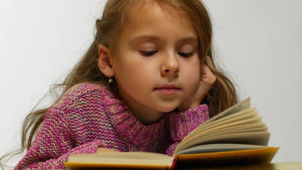 View of a Girl Reading a Book. A Young Cute Girl Reads a Book in a Whisper