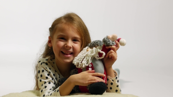 Portrait of Happy Girl Hugging Santa Claus Toy. Funny Young Girl Waving Hello
