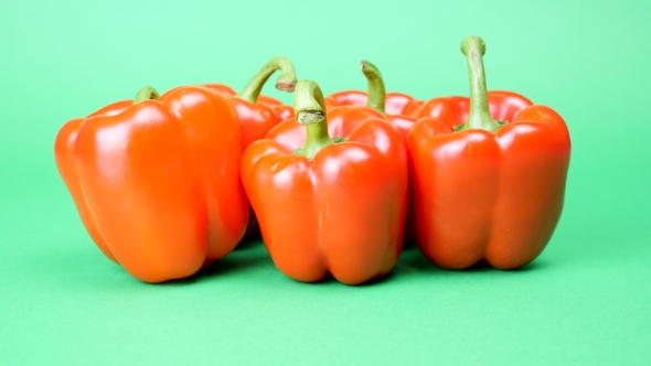 Five Red Sweet Peppers on Green Background