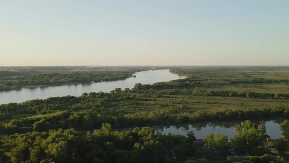 Aerial parallax of Zarate large green fields and forest area and Parana river flowing into horizon a