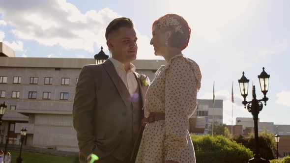 Beautiful Couple of Bride and Groom are Kissing Against Backdrop of Cloud Blue Sky