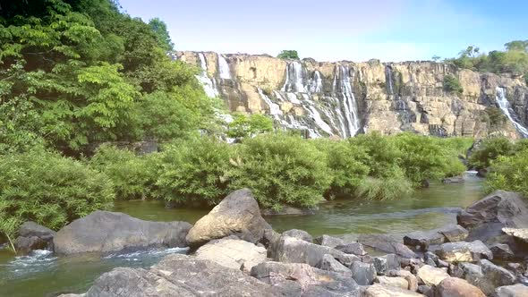 Stones and Brushwoods in Mountain River Against Waterfall