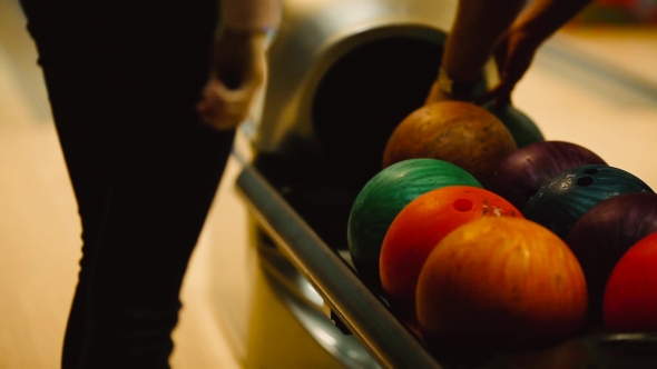 The Girl Is Waiting for the Machine To Give Out Balls for Bowling