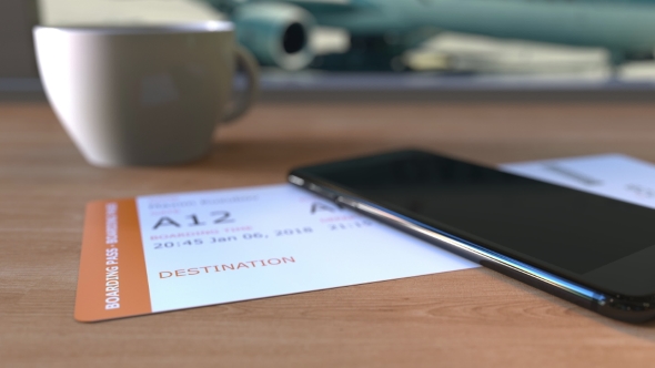 Boarding Pass To Basra and Smartphone on the Table in Airport While Travelling To Iraq