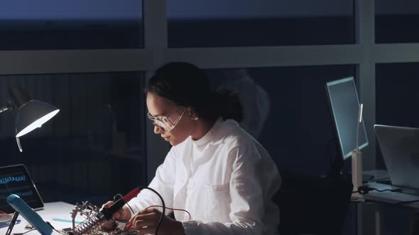 Middle Close Up of African American Engineer Making Tests on Motherboard in Lab. Scientist Working