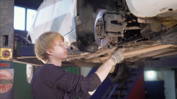 a Young Male Mechanic Engaged in Repairing the Wheels of the Vehicle