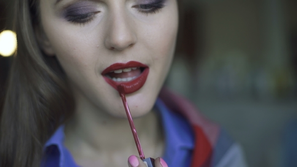 Young Beautiful Woman Applying Her Bordo Lipstick at a Mirror