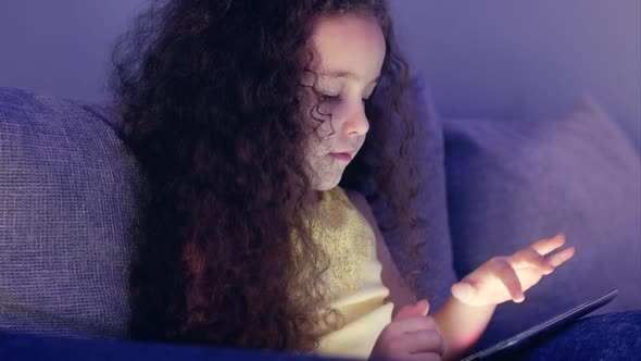 Cute Little Girl Spending Leisure Time Playing Mobile Game in the and Crushes the Bright Screen