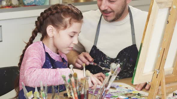 Cropped Shot of a Cute Little Girl Smiling Talking To Her Dad Mixing Paints at Art Class