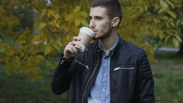 Handsome Male Model Drinks Coffee in a Autumn Park