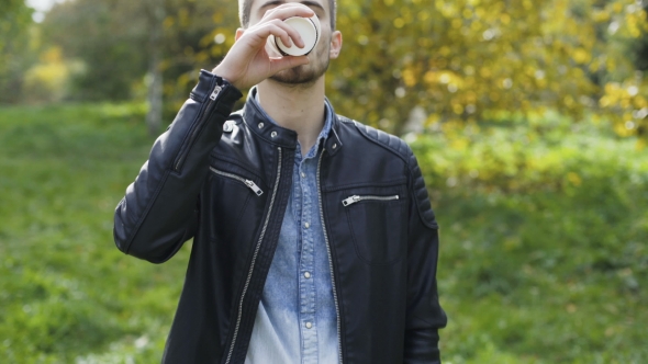 Handsome Male Model Drinks Coffee in a Fresh Autumn Park
