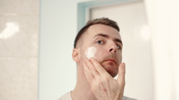 Young Man Applies a Shaving Foam on His Face