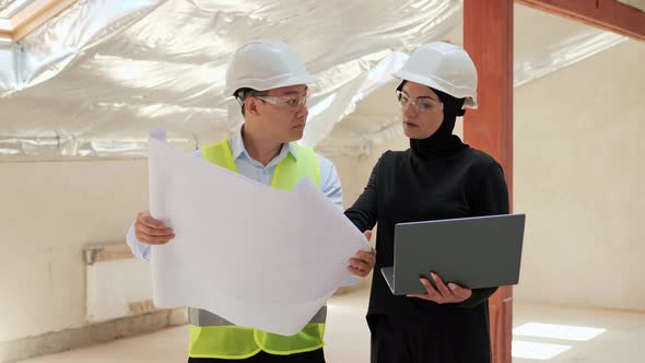 Muslim Female Investor Wearing a Hijab Talking to Asian Engineer