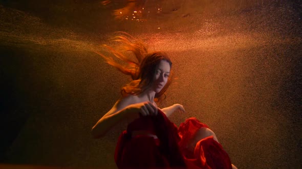 Portrait of a Beautiful Girl in a Flowing Red Suit-a Long Skirt and Top She Is Underwater on an