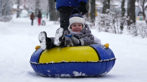Boy of Two Years Rolling on Tubing in the Park in Winter.