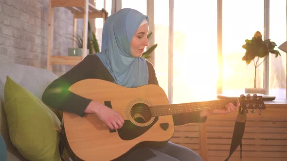 Portrait Young Muslim Woman Sitting on the Couch Playing Guitar