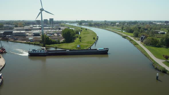 A Flat-bottomed Boat Cruising The Tranquil Waters Of Gouwe River With Wind Turbine On Sight And Pano