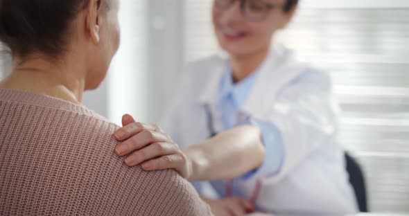 Female Doctor Holding Aged Patient By Shoulder Soothing Her Fear