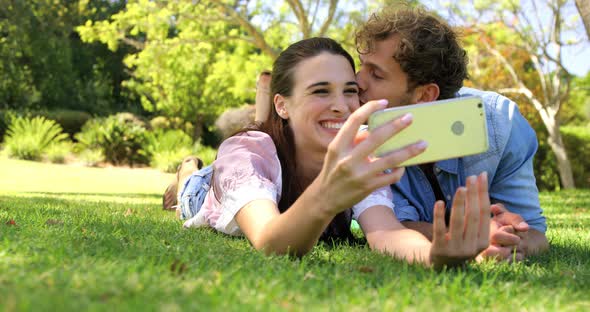 A couple lying on the grass taking a selfie