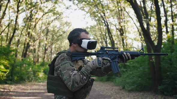 Soldier with Rifle Wearing Virtual Reality Glasses Outdoors