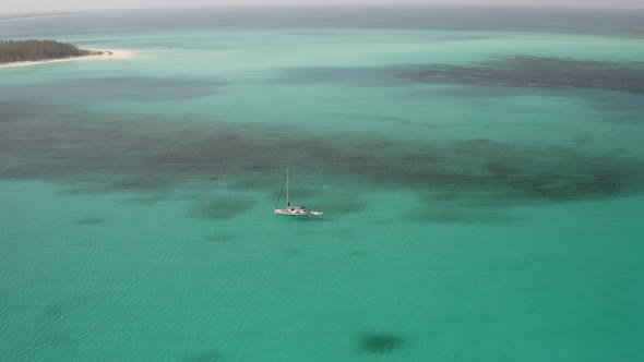 Aerial View of Sailboat in Turquoise Tropical Water by Coast Of Grand Bahamas Island, Drone Shot
