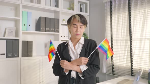Portrait of Asian businessman gay working in office, holding LGBT flag.