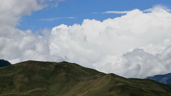 Timelapse Clouds Swirl Over a Green Mountain Valley