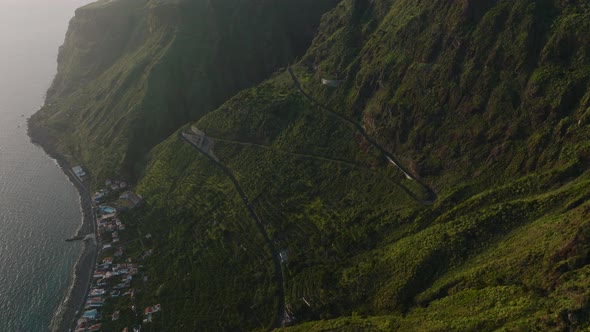 Curvy road down steep mountainside and terraced farm land, Madeira; aerial