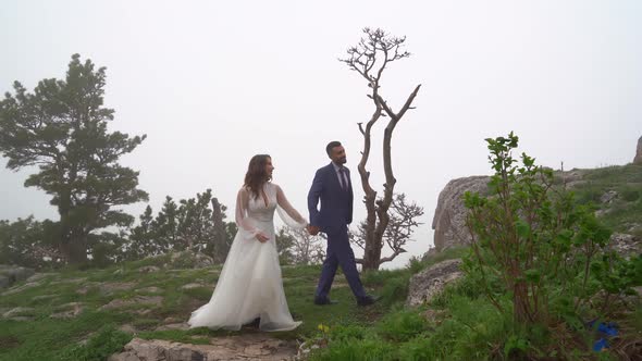Bride and Groom Holding Hands in a Misty Mountain Forest
