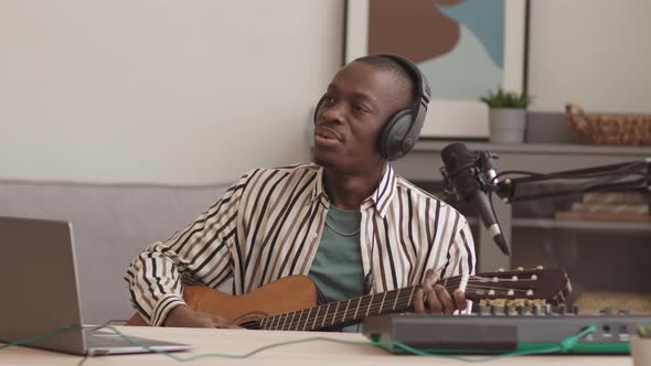 African Musician Playing Guitar and Signing at Home